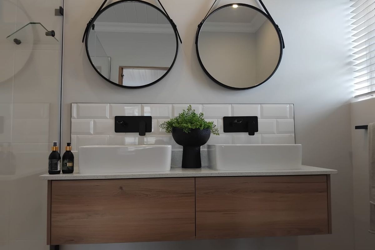 Modern bathroom featuring a floating double vanity with vessel sinks, matte black wall-mounted faucets, and subway tile backsplash.