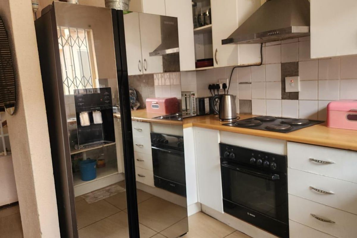 A functional kitchen featuring white cabinetry, a built-in oven with electric hob, extractor fan, and tiled backsplash with laminate countertops.