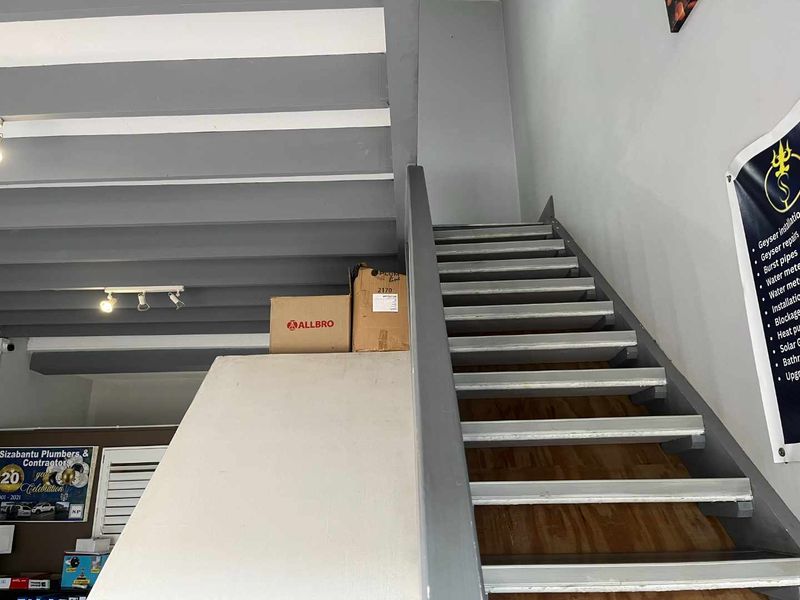 An interior view of a staircase with exposed ceiling beams, showing a functional industrial-style layout.