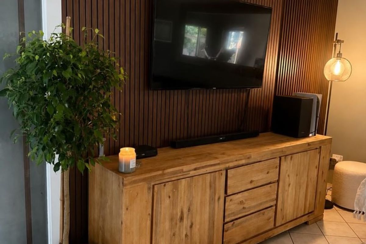 A living room area featuring modern vertical slatted timber wall paneling and neutral tiled flooring.
