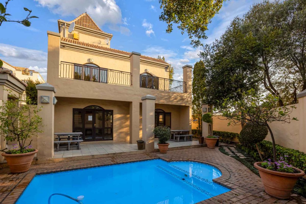 Rear view of the apartment featuring a private swimming pool, paved patio area, and a balcony overlooking the garden.