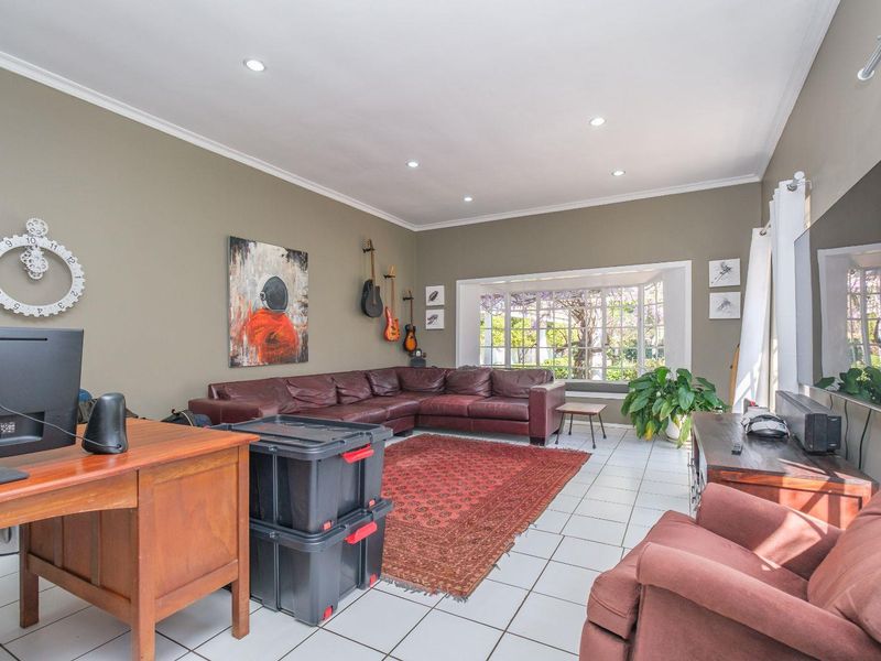 Spacious living room featuring tiled flooring, recessed downlights, and a large bay window allowing for natural light.