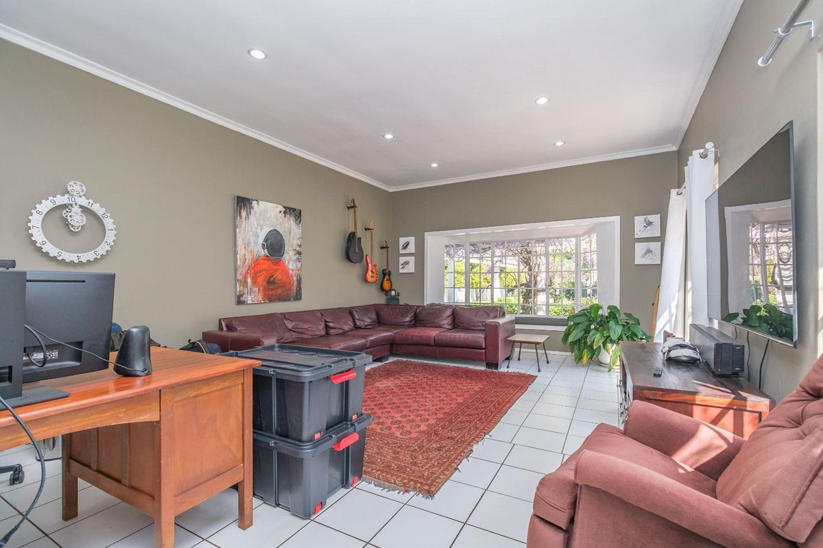 Spacious living room featuring tiled flooring, recessed downlights, and a large bay window allowing for natural light.