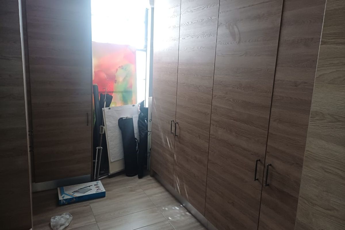 A bedroom space featuring extensive built-in wooden cabinetry and tiled flooring, offering ample storage and a clean, neutral aesthetic.