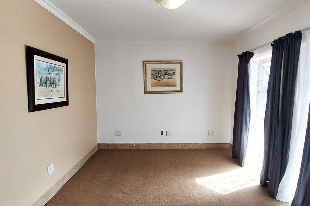 A bright, empty living room featuring carpeted flooring and a sliding glass door providing access to the exterior.