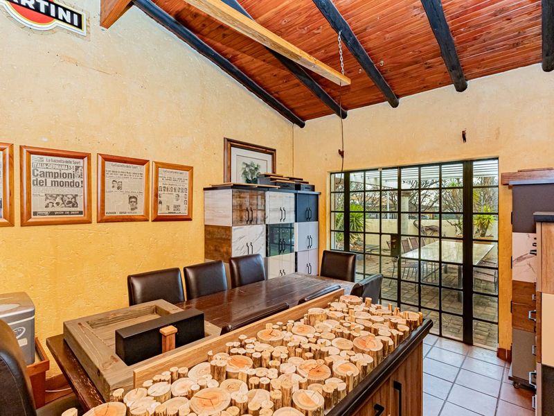 Living area featuring exposed timber ceiling beams, tiled flooring, and large steel-framed glass doors providing access to the outdoor patio.