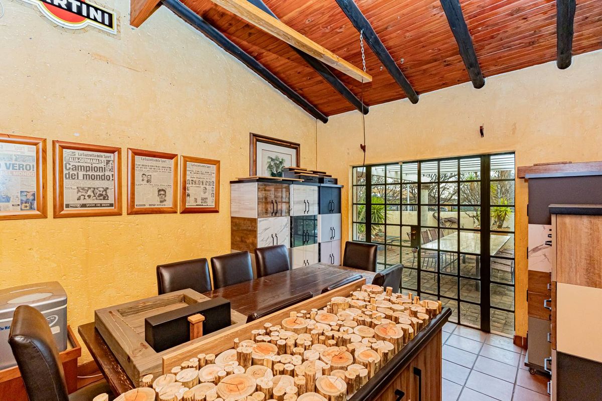 Living area featuring exposed timber ceiling beams, tiled flooring, and large steel-framed glass doors providing access to the outdoor patio.