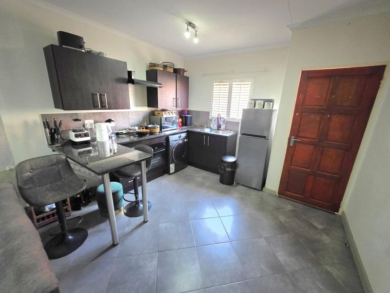 A functional kitchen featuring dark wood cabinetry, granite countertops, tiled flooring, and a direct access timber door.