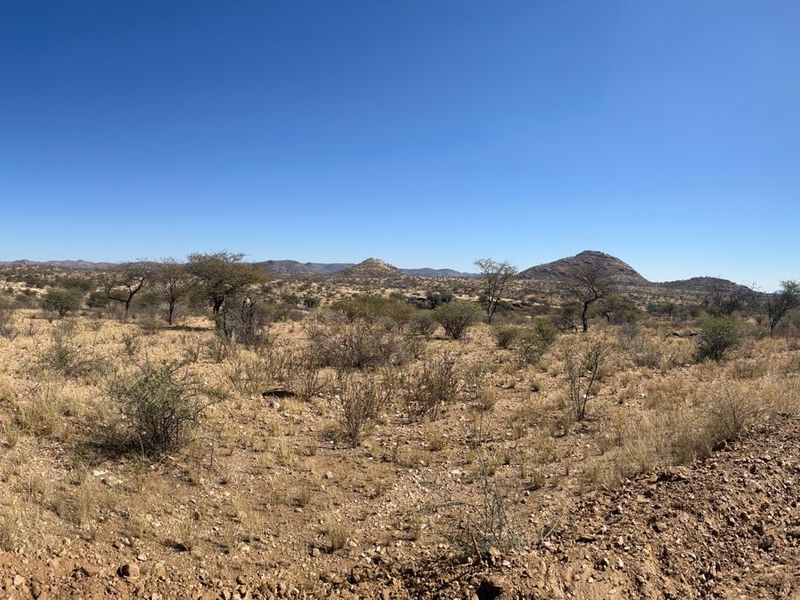 A panoramic view of the expansive, arid landscape featuring natural vegetation and a dirt access road.