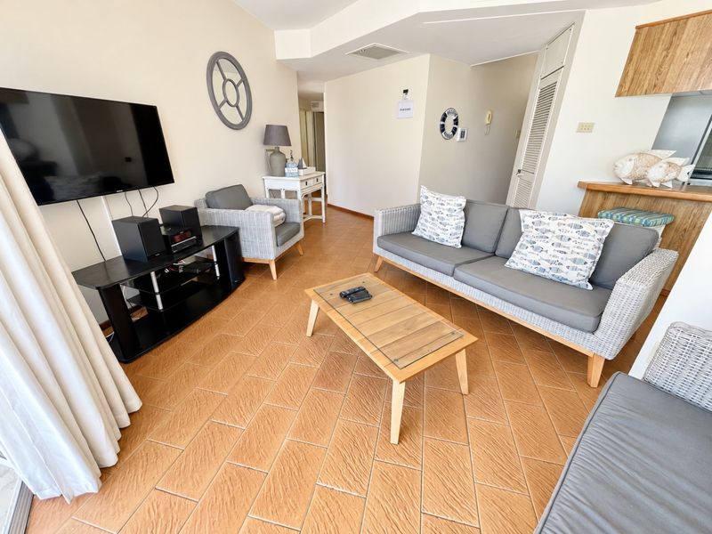 Open plan living area featuring tiled flooring and a breakfast bar connecting to the kitchen space.