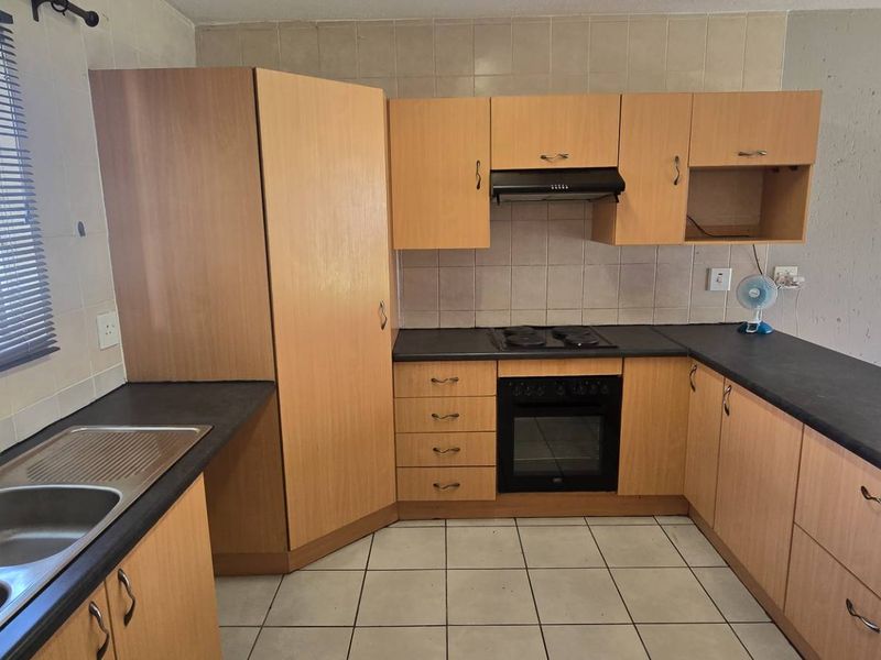 A functional kitchen featuring built-in cabinetry, dark laminate countertops, a built-in oven with hob, and tiled flooring throughout.