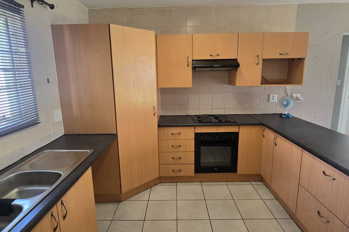 A functional kitchen featuring built-in cabinetry, dark laminate countertops, a built-in oven with hob, and tiled flooring throughout.