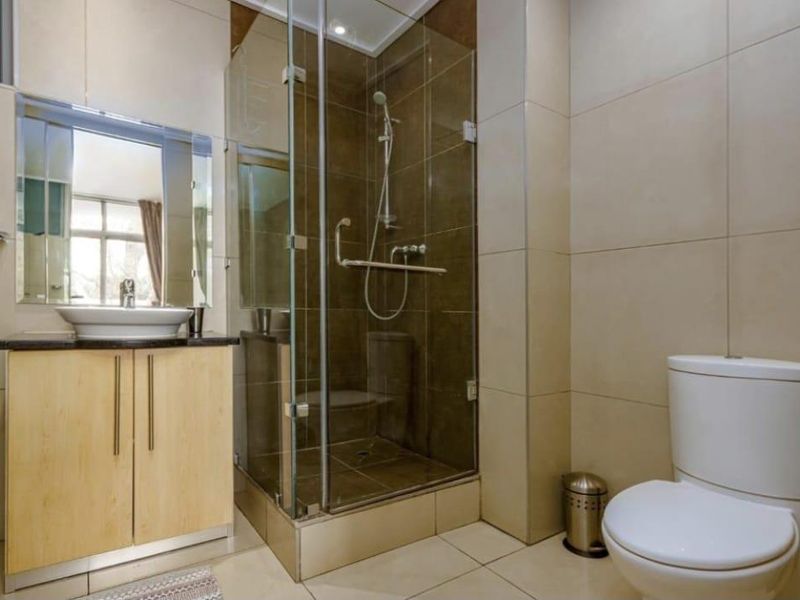 Modern bathroom featuring a glass-enclosed shower, vanity with vessel sink, and neutral floor-to-ceiling tiling.
