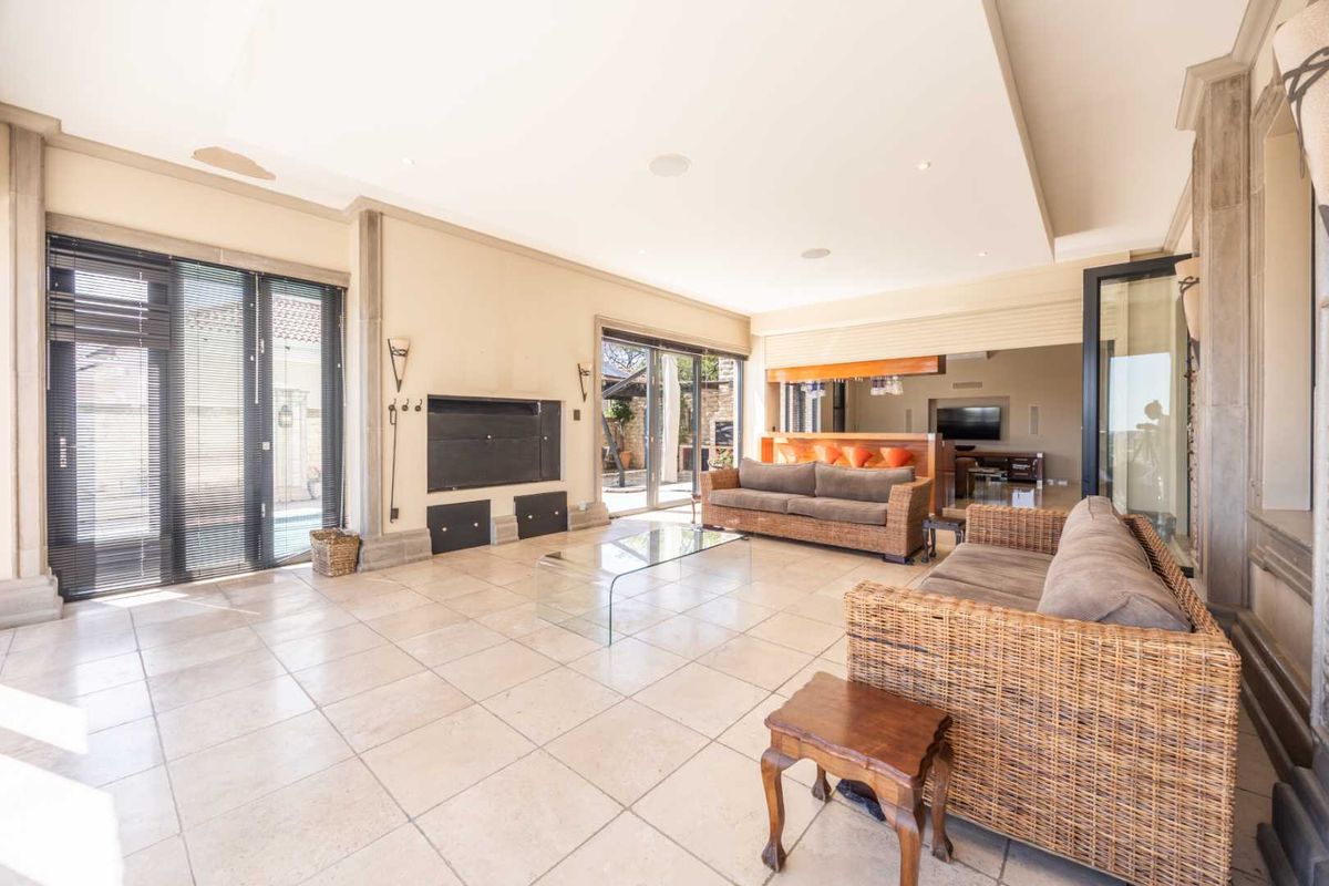 Spacious living room featuring large format floor tiles, recessed ceiling lighting, and built-in fireplace, with seamless access to the outdoor area through sliding glass doors.