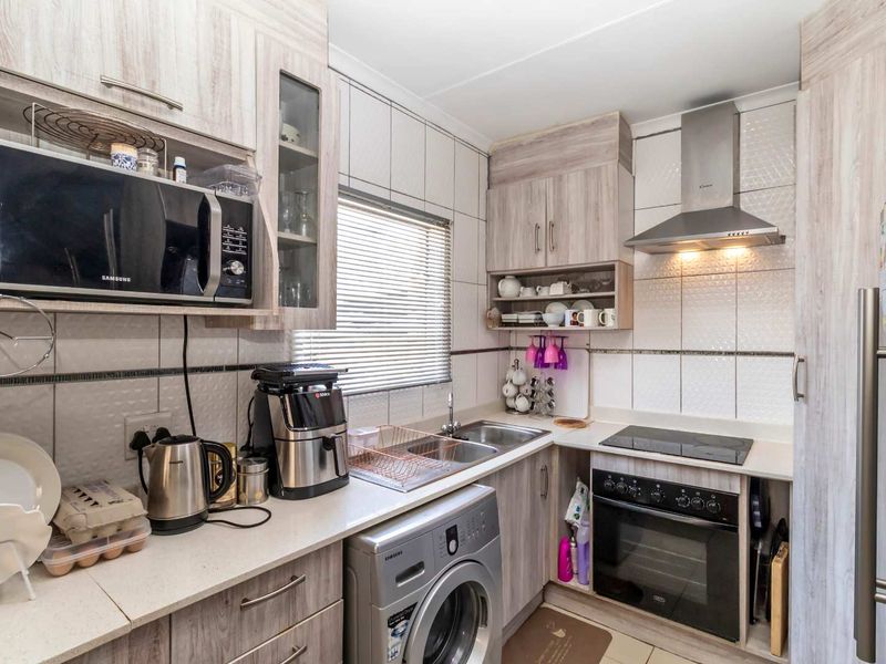 Compact kitchen featuring light wood-grain cabinetry, integrated appliances including an oven and hob, and a tiled backsplash with ample counter space.