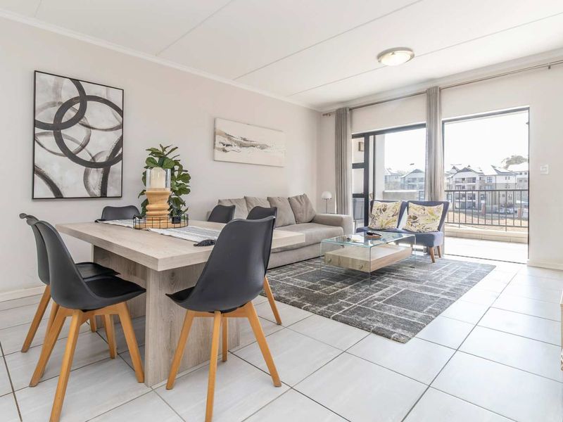 Bright open-plan living and dining area featuring neutral tiled flooring and large sliding glass doors providing direct access to the balcony.