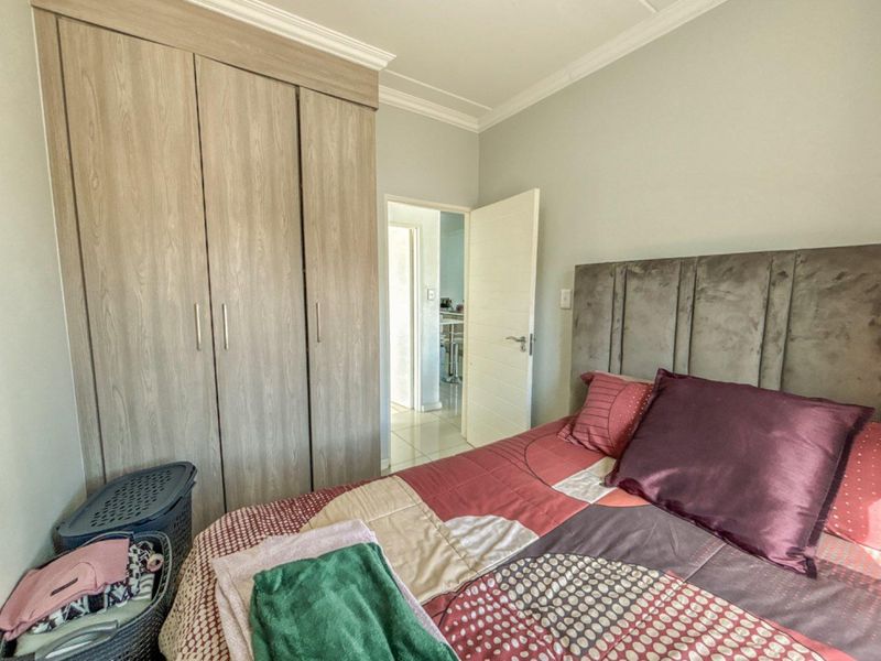 A well-maintained bedroom featuring built-in wooden cupboards, crown molding, and a neutral color palette, providing a functional and comfortable living space.