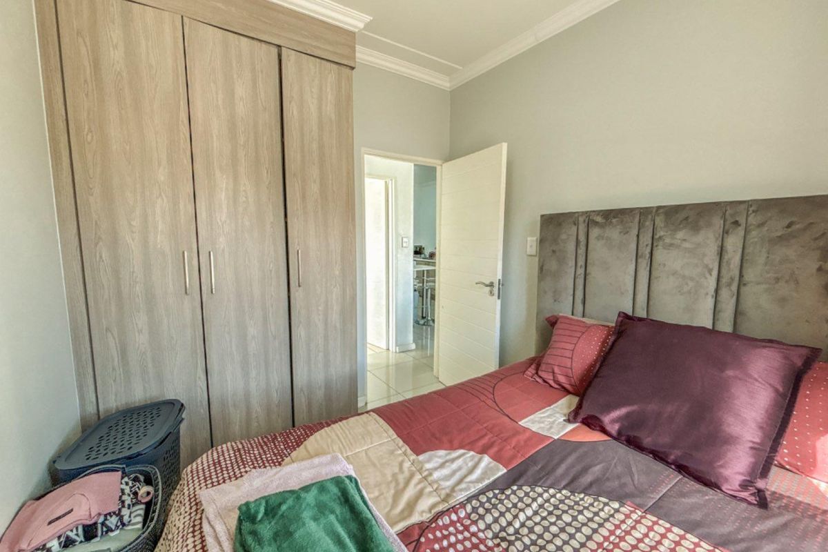 A well-maintained bedroom featuring built-in wooden cupboards, crown molding, and a neutral color palette, providing a functional and comfortable living space.