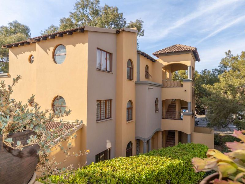 Exterior view of a multi-story apartment building featuring Mediterranean-style architecture with stucco walls, arched windows, and private balconies.