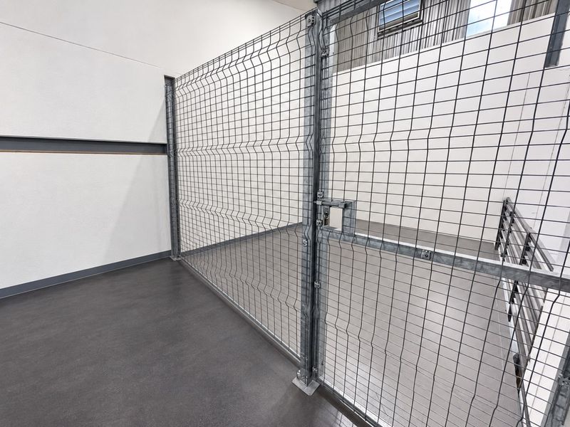 A clean, secure utility storage area featuring wire mesh partitioning and durable flooring, suitable for organized storage or industrial use.