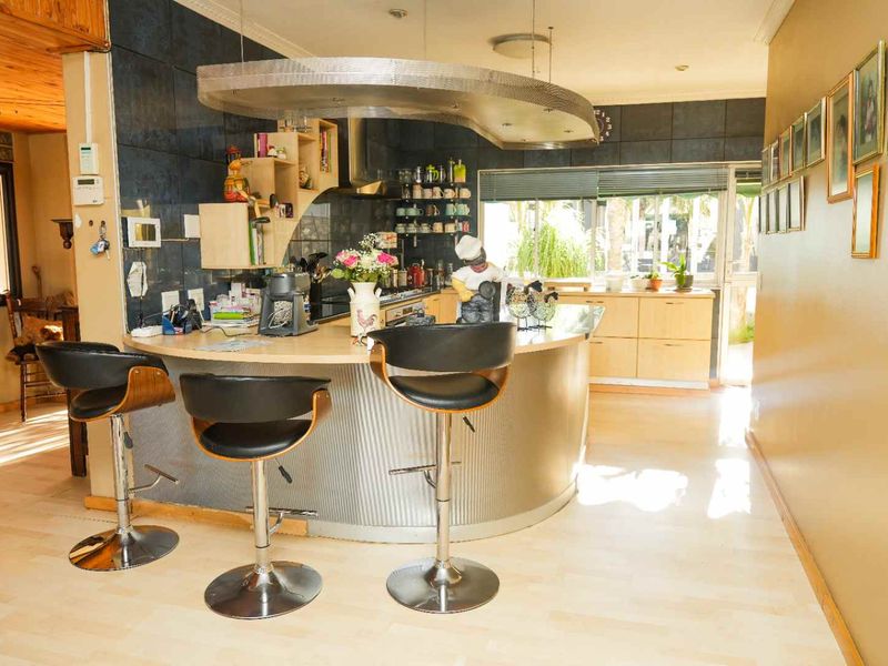 A unique kitchen featuring a curved breakfast bar, modern cabinetry, and a distinctive stainless steel extractor hood, offering a functional and characterful cooking space.