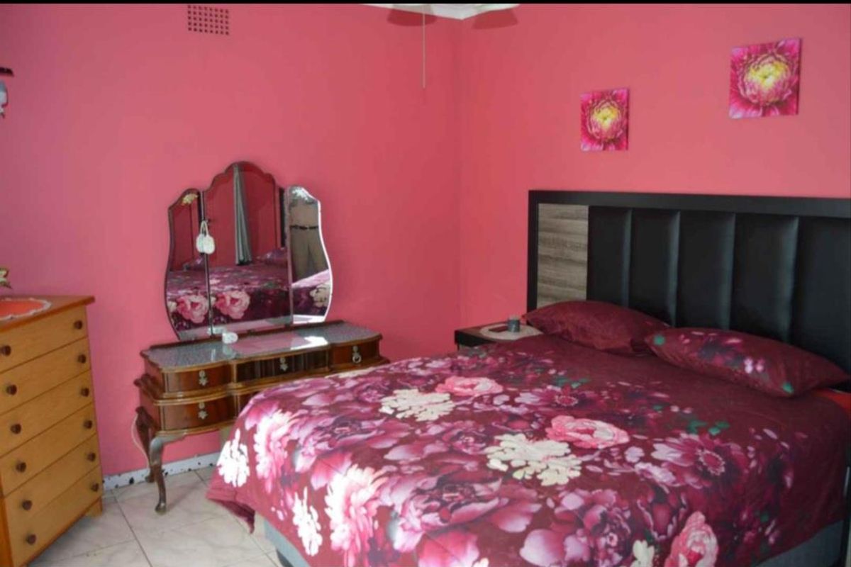 A bedroom featuring tiled flooring and a ceiling fan, finished with bold pink wall paint.