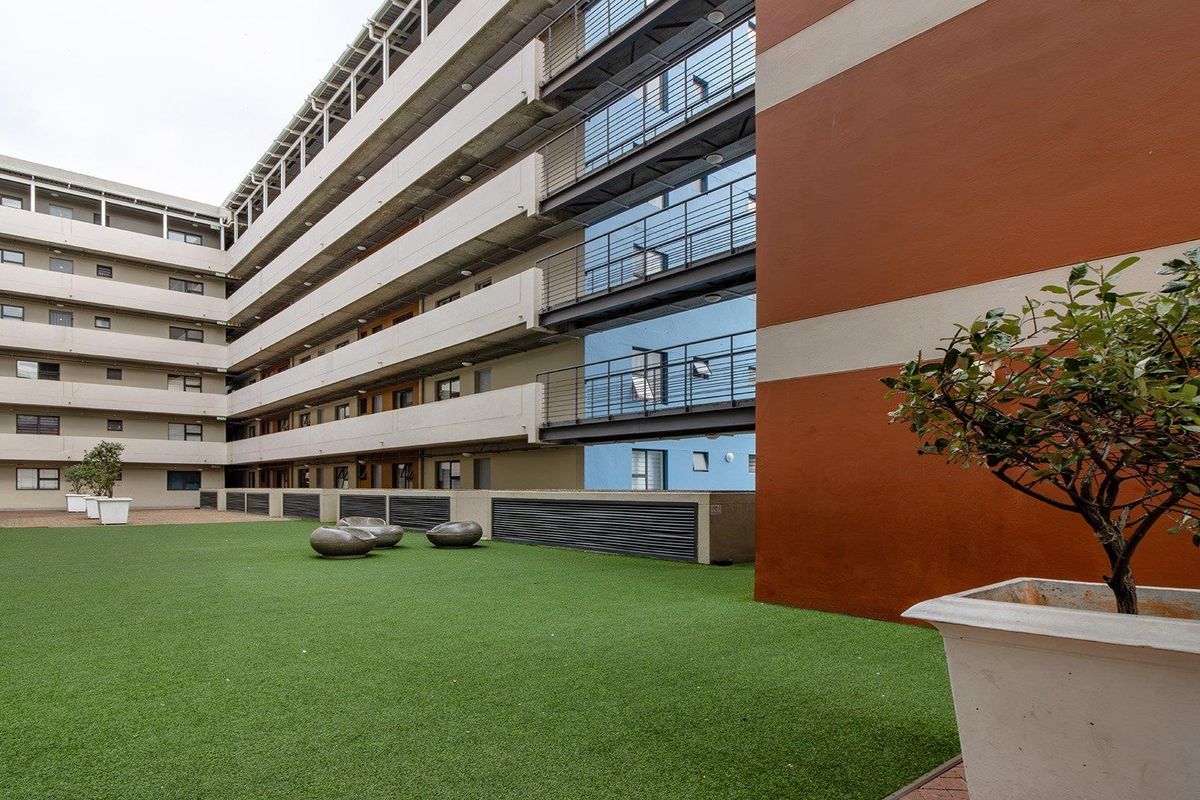A view of the apartment complex courtyard featuring artificial turf, paved areas, and multi-story building facades with metal balcony railings.