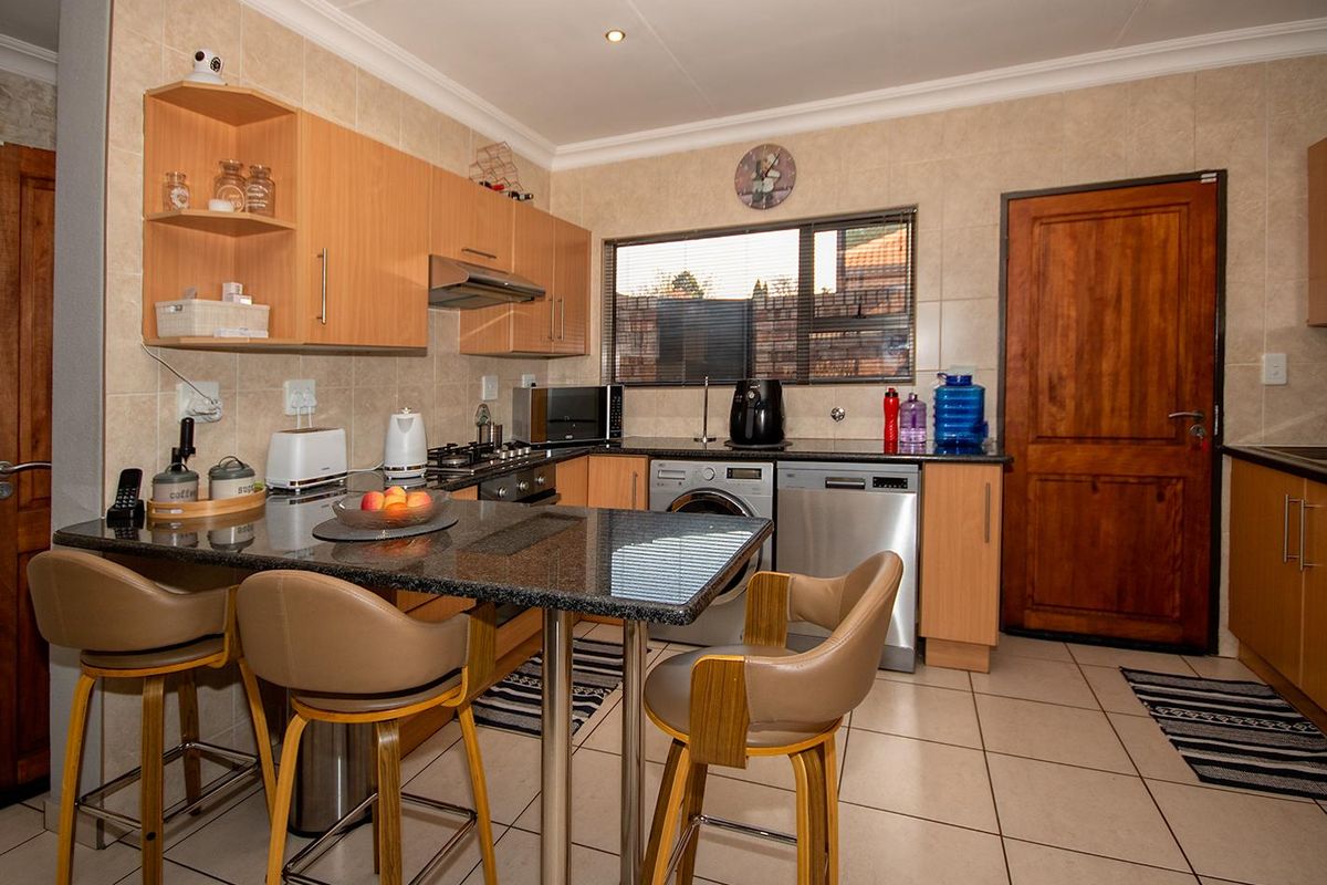 Functional kitchen featuring granite countertops, tiled backsplash, ample cabinetry, and a breakfast bar area with integrated appliance spaces.