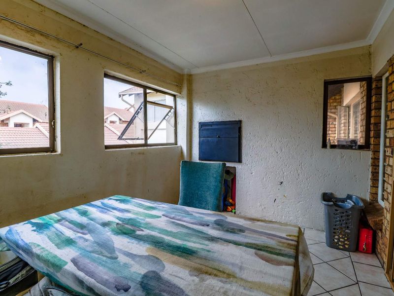 A living area featuring tiled flooring, a built-in wall safe, and security gate access, requiring cosmetic updates to the wall finishes.