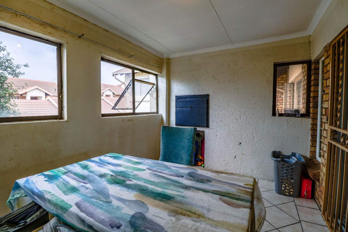 A living area featuring tiled flooring, a built-in wall safe, and security gate access, requiring cosmetic updates to the wall finishes.