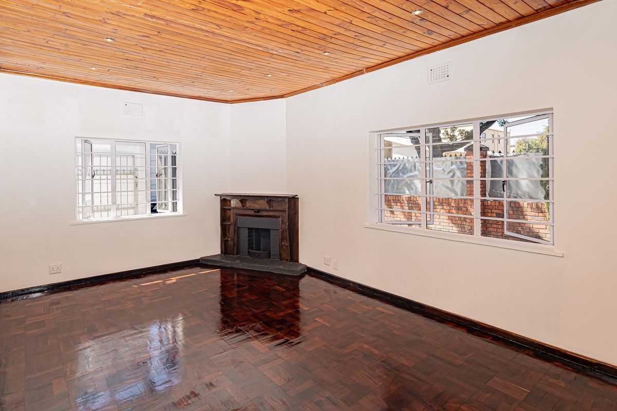 Spacious living room featuring polished parquet flooring, a classic fireplace, and a warm timber-clad ceiling with recessed lighting.