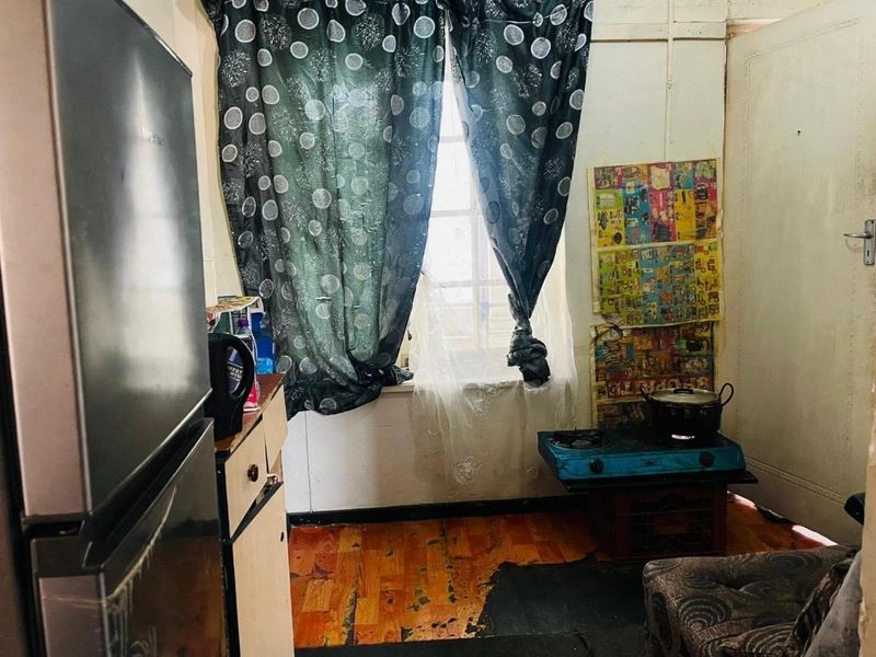 A small kitchen area featuring worn flooring and basic finishes, requiring significant renovation and modernization to improve functionality and aesthetic appeal.