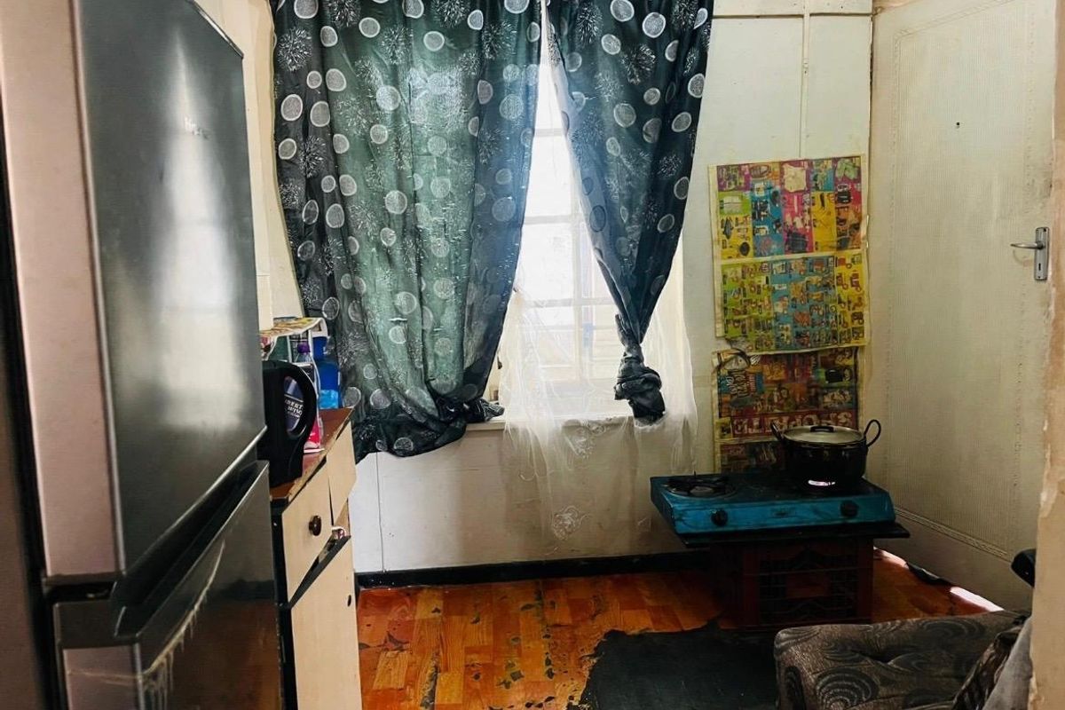 A small kitchen area featuring worn flooring and basic finishes, requiring significant renovation and modernization to improve functionality and aesthetic appeal.