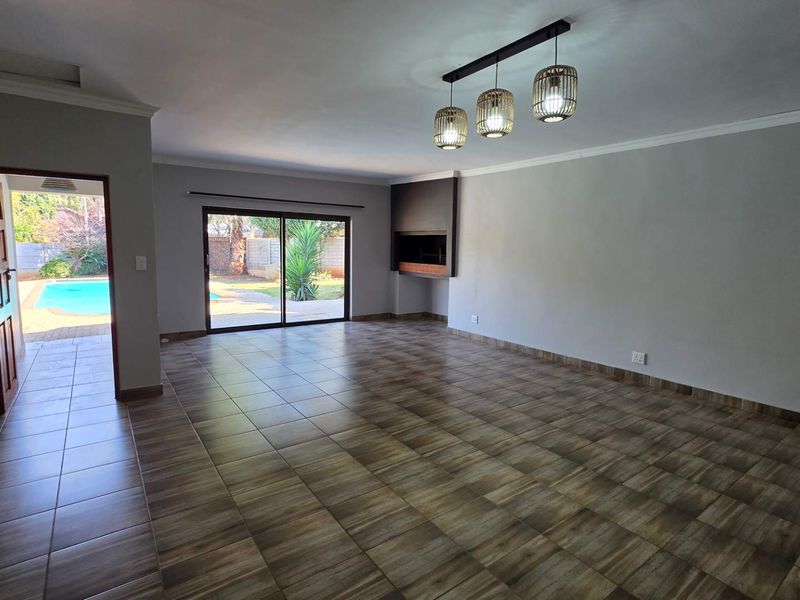 Spacious, empty living area featuring tiled flooring, a built-in fireplace, and sliding glass doors providing direct access to the outdoor pool area.