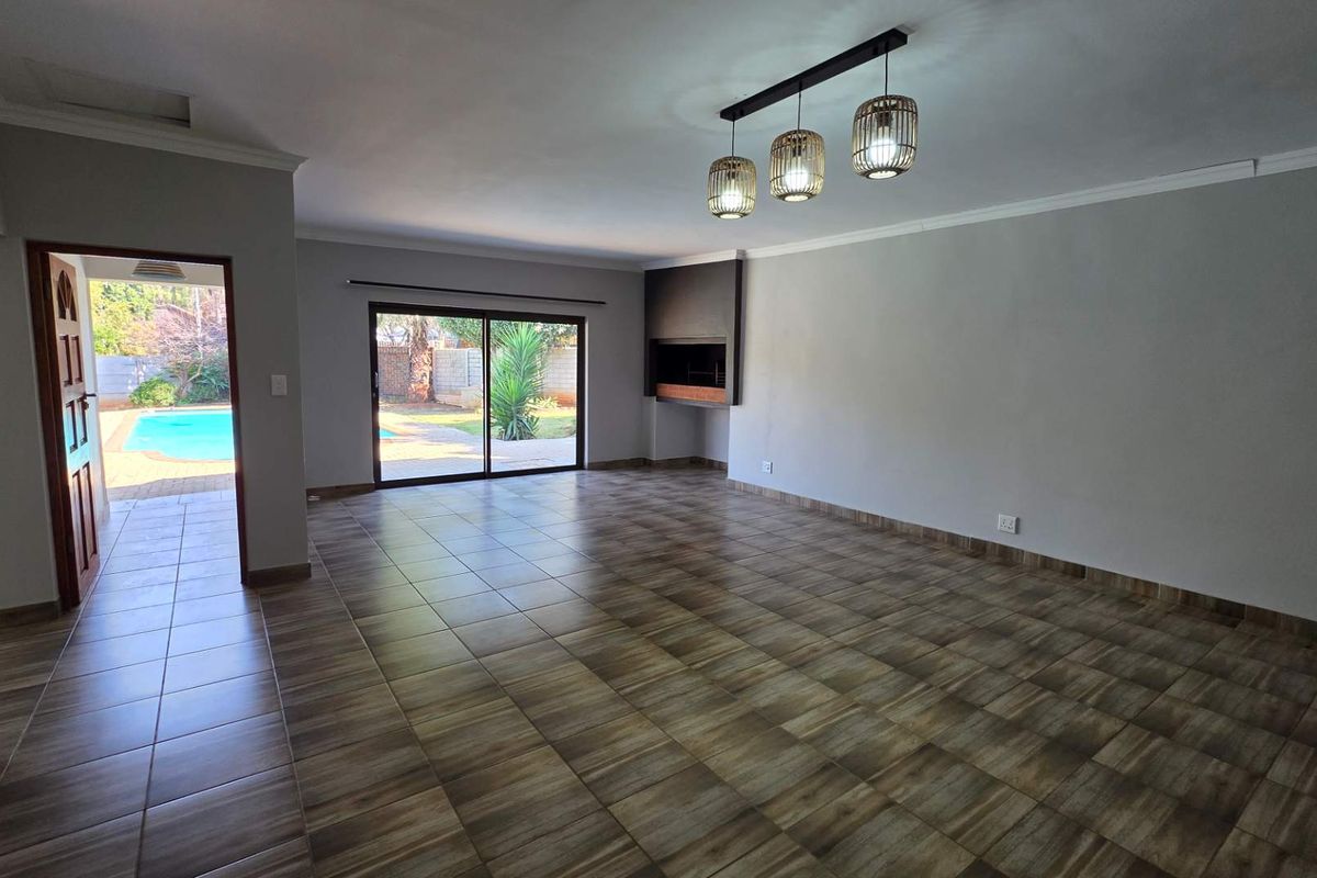 Spacious, empty living area featuring tiled flooring, a built-in fireplace, and sliding glass doors providing direct access to the outdoor pool area.
