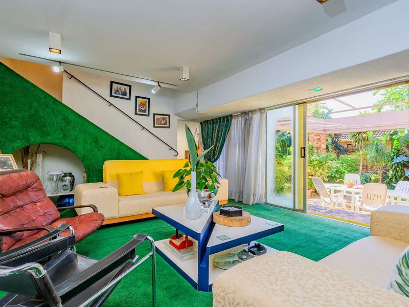 A living room featuring a staircase, track lighting, and large sliding glass doors that provide direct access to an outdoor patio area.