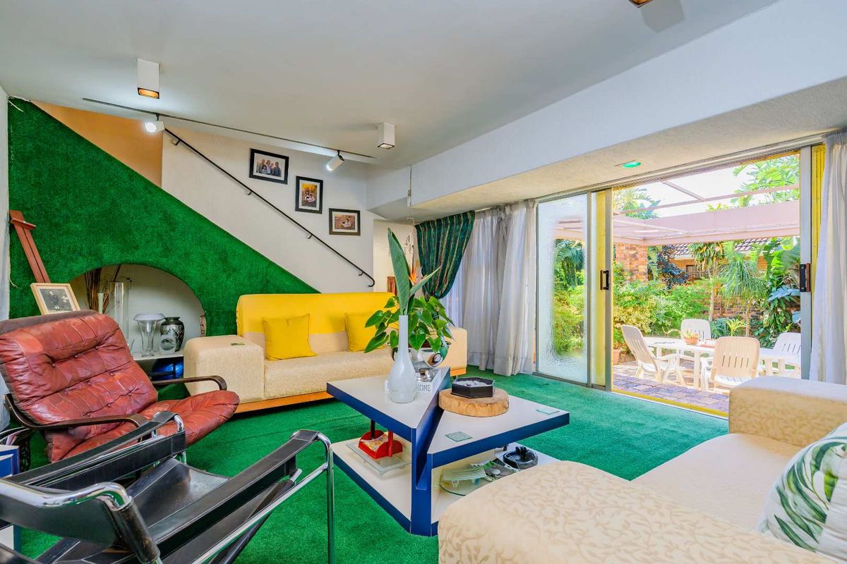 A living room featuring a staircase, track lighting, and large sliding glass doors that provide direct access to an outdoor patio area.