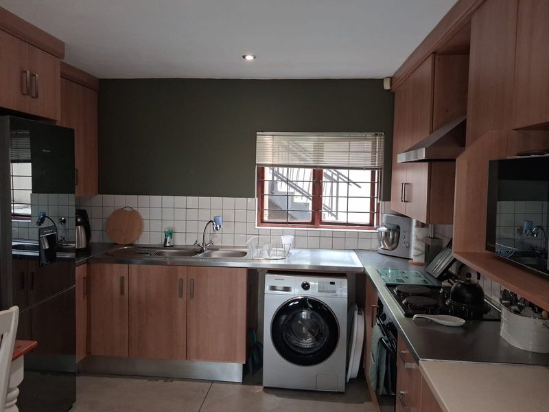Functional kitchen featuring laminate cabinetry, stainless steel countertops, integrated appliances, and a tiled backsplash with a window providing natural light.