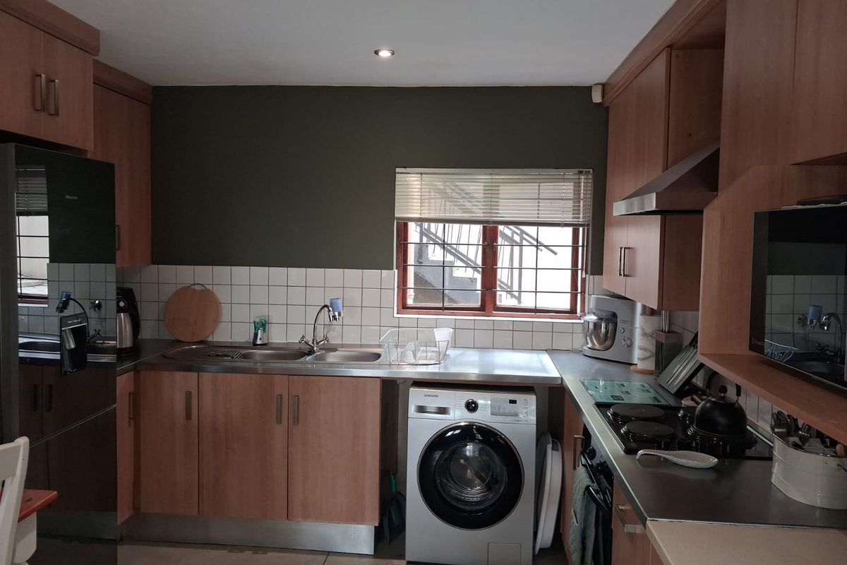 Functional kitchen featuring laminate cabinetry, stainless steel countertops, integrated appliances, and a tiled backsplash with a window providing natural light.