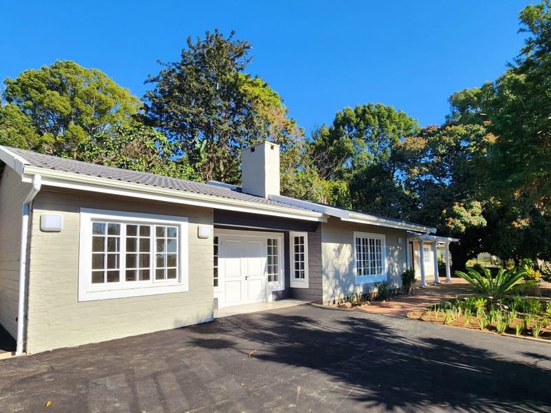 Front elevation of a well-maintained townhouse featuring a paved driveway, covered veranda with columns, and classic lattice-style windows.