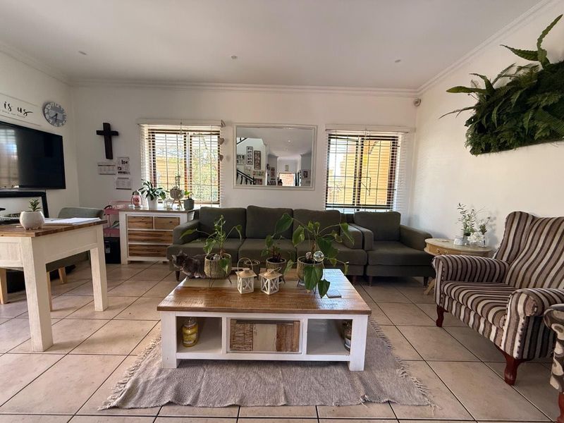 A spacious living room featuring tiled flooring, recessed downlighting, and large windows with venetian blinds, offering a bright and comfortable living environment.