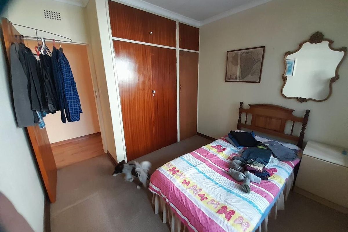 A functional bedroom featuring built-in wooden cupboards and neutral wall finishes, offering a practical layout for a comfortable sleeping space.