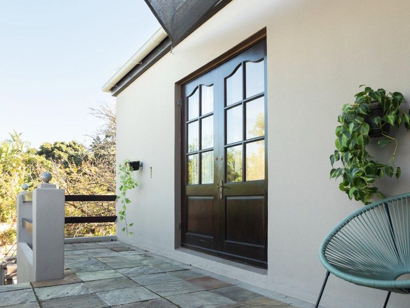 A well-maintained balcony featuring stone tile flooring, a secure balustrade, and elegant double glass panel doors leading into the apartment.