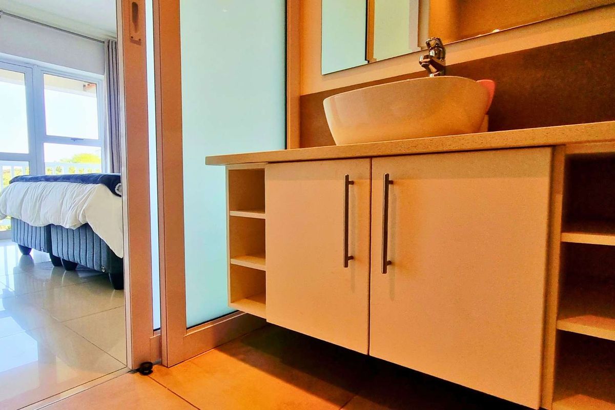 A modern bathroom vanity featuring a vessel sink and integrated storage, adjacent to a bedroom with sliding glass door access.