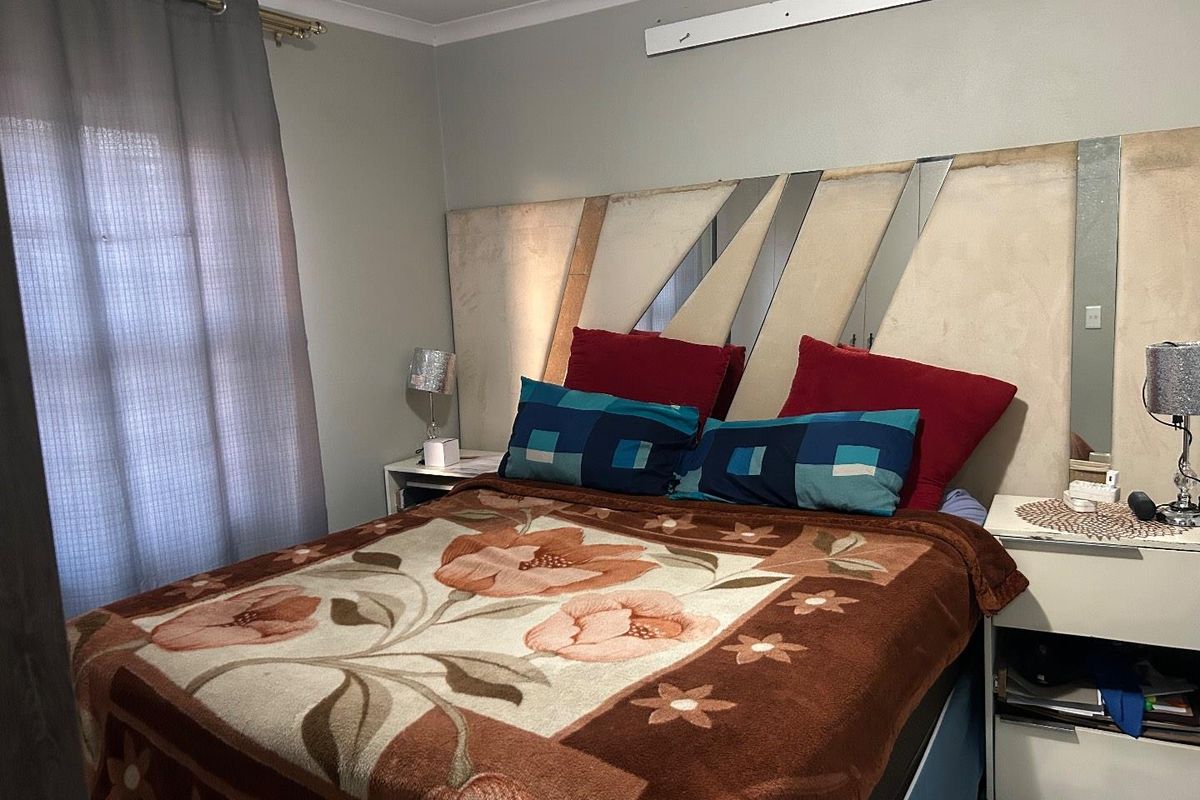 A bedroom featuring a custom headboard wall design with integrated mirrors and neutral wall tones.