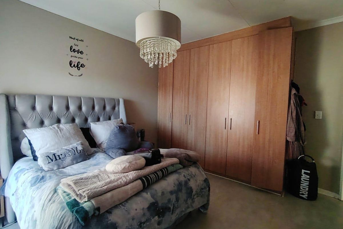 A bedroom featuring built-in wooden cupboards and a central pendant light fixture.