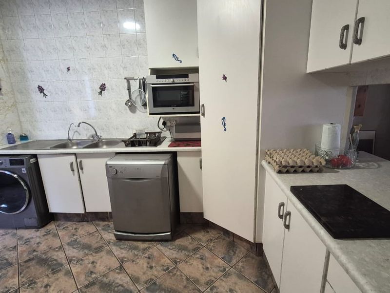 A functional kitchen featuring built-in cabinetry, laminate countertops, a stainless steel sink, and tiled finishes, offering potential for a modern renovation.