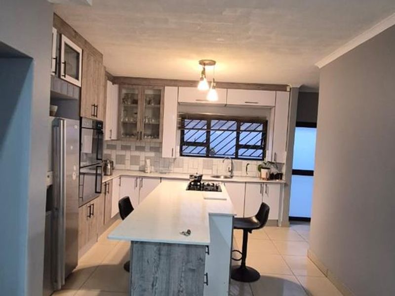 Modern kitchen featuring a central island with a gas hob, built-in oven, ample cabinetry, and tiled flooring.