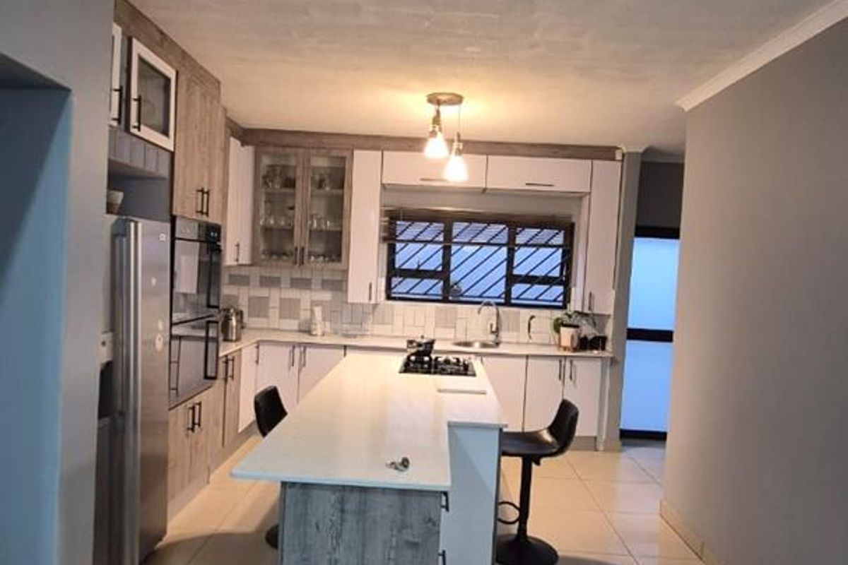 Modern kitchen featuring a central island with a gas hob, built-in oven, ample cabinetry, and tiled flooring.