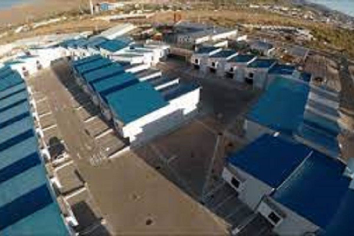 Aerial view of an industrial complex featuring multiple warehouse units with blue metal roofing and paved access roads.